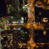 An aerial shot of a city scape at night time, street lights are on and cars are on the roads