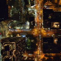 An aerial shot of a city scape at night time, street lights are on and cars are on the roads