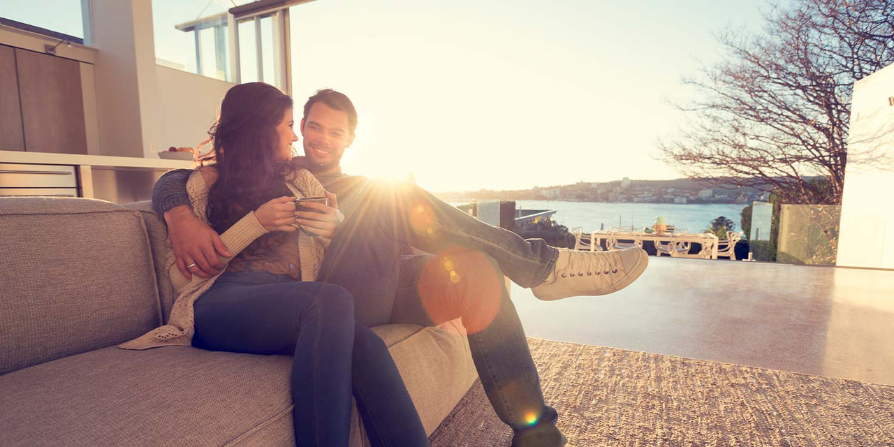 Artisan Coffee Co Health Benefits hader couple drinking coffee lon an outside couch with the sun in the background giving off some lense flare