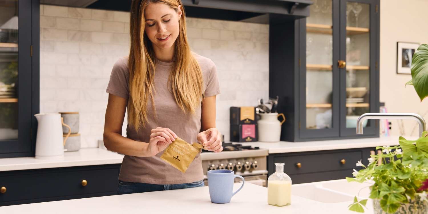 A woman in a kitchen making The Smart Cookie Coffee Bag with a blue mug
