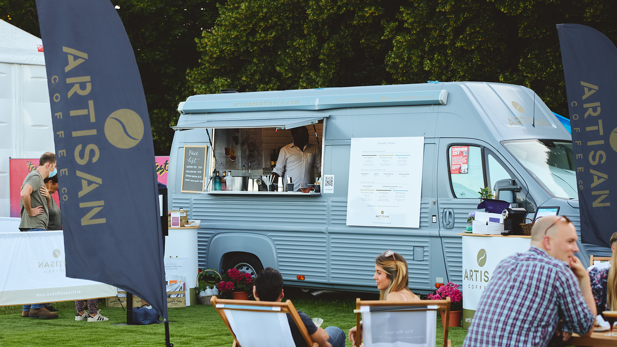 Arty, the Artisan Coffee Co Coffee van at an event with lounge chairs and Artisan flags
